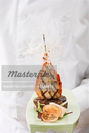 Chef holding Surf & Turf (beef steak with prawn) on platter Chef holding Surf & Turf (beef steak with prawn) on platter