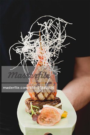 Man holding Surf & Turf (beef steak with prawn) on platter Man holding Surf & Turf (beef steak with prawn) on platter