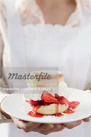 Chambermaid serving strawberry shortcake on plate