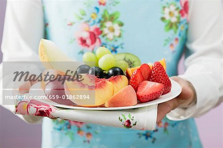 Femme qui dessert une assiette de fruits frais