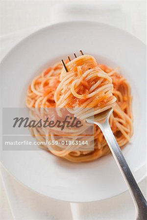 Spaghetti with tomato sauce on fork and plate