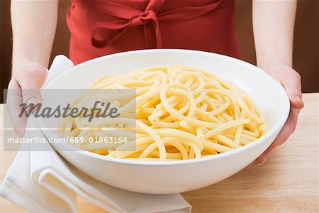 Woman holding bowl of cooked macaroni