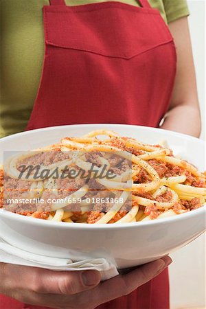 Woman holding bowl of macaroni with mince sauce