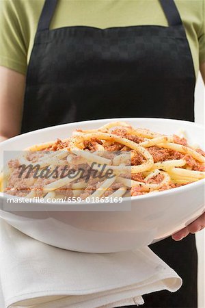 Person holding bowl of macaroni with mince sauce