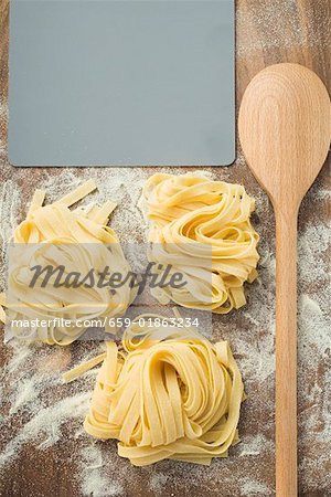 Home-made ribbon pasta beside wooden spoon