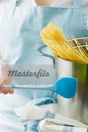 Woman holding kitchen spoon and pan with spaghetti