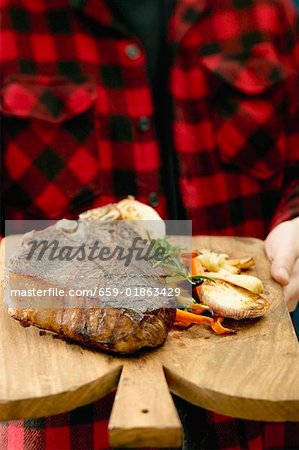 Man serving grilled T-bone steak on chopping board Man serving grilled T-bone steak on chopping board