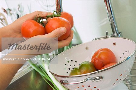 Freshly washed tomatoes in colander in sink