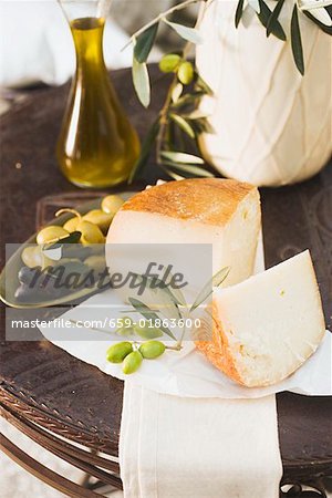 Cheese, olives and olive oil on table out of doors