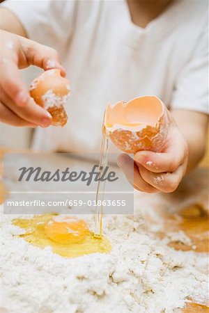 Making pasta dough: a child breaking an egg