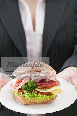 Woman holding a ham and cheese sandwich on a plate