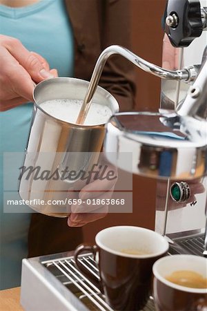 Woman frothing milk with espresso machine