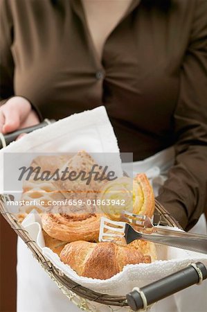 Woman in apron holding basket of sweet pastries