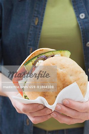Woman holding toasted roll filled with grilled vegetables