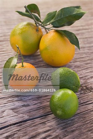 Oranges, clémentines et citrons verts sur fond en bois