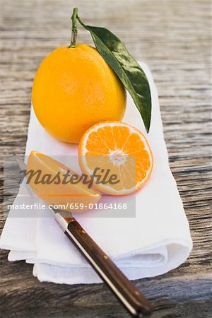 Orange complet et les deux moitiés d'oranges sur un tissu blanc