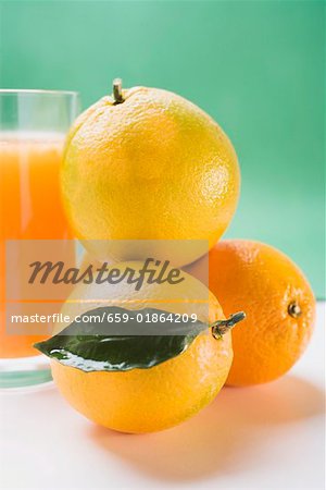 Verre de jus d'orange à côté de plusieurs oranges