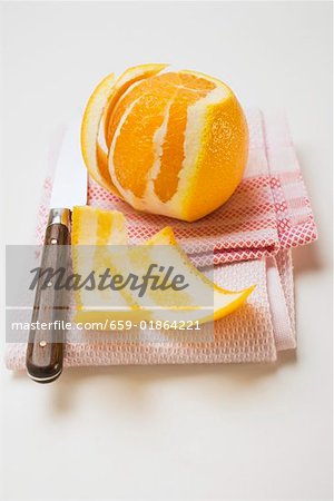 Peeled orange on tea towel with knife