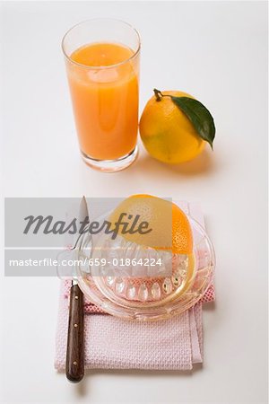 Squeezing an orange, glass of orange juice & whole orange