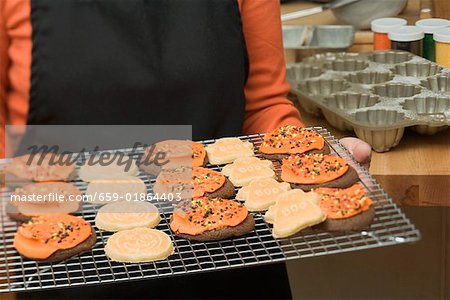 Woman holding Halloween biscuits on cake rack