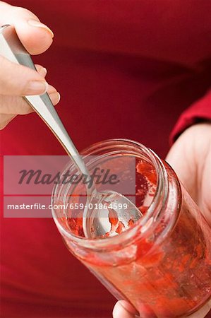 Femme tenant presque vide pot de confiture de fraises