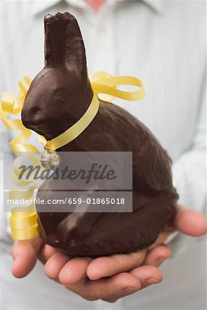 Mains tenant le lapin de Pâques au chocolat