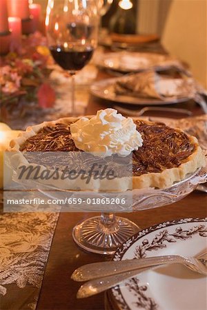 Tarte aux pacanes avec de la crème sur une table posée pour Thanksgiving (USA)