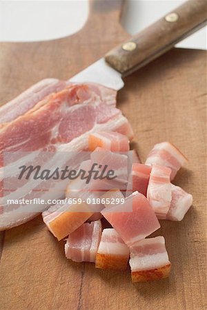 Tranches de bacon & lardons sur planche à découper avec couteau