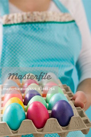Femme tenant un œufrier plein de œufs de Pâques colorés