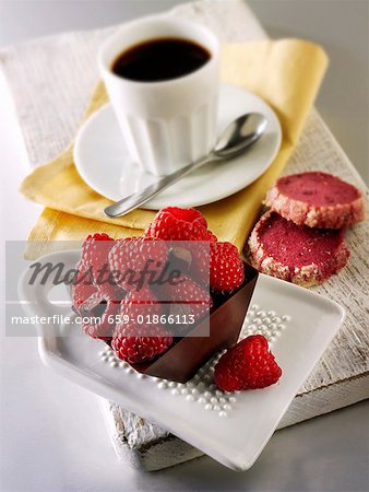 Kleiner Schokoladenkuchen mit Himbeeren und Tasse Kaffee