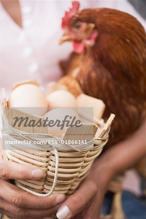Woman holding live hen and basket of eggs