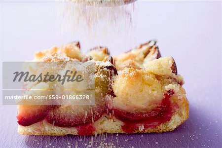 Stück Kuchen Pflaumen mit Zucker bestreuen