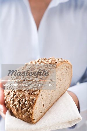 Woman holding sunflower bread (part of a loaf)