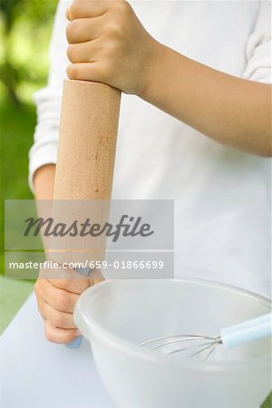 Child's hands holding rolling pin bowl & whisk beside him