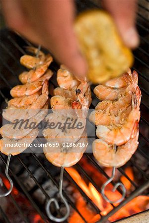Hand Auspressen Zitronensaft über Garnelen-Spieße am Grill rack Hand Auspressen Zitronensaft über Garnelen-Spieße am Grill rack