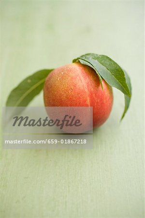 Nectarine with leaves on green background