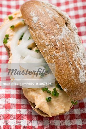 Bread roll with Obatzda (Camembert spread) & onions on checked cloth