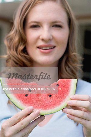 Young woman holding a slice of watermelon with bites taken