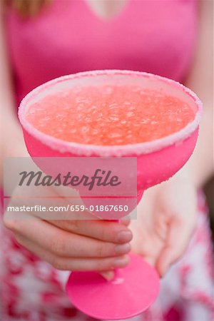 Femme tenant un cocktail dans un verre rose