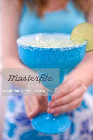 Femme tenant une lime cocktail dans un verre turquoise