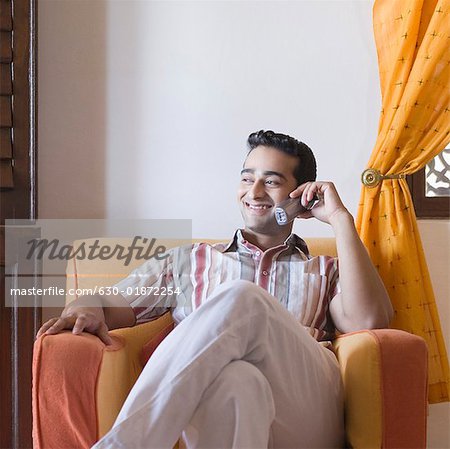 Jeune homme parlant sur un téléphone mobile et souriant