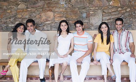 Portrait de trois jeunes couples assis sur un banc et souriant