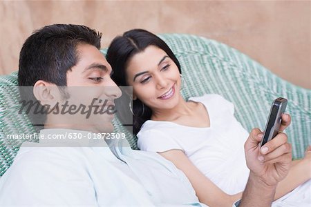 Nahaufnahme eines jungen Paares, Blick auf ein Mobiltelefon und Lächeln