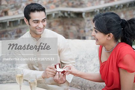 Close-up of a young man giving an engagement ring to a young woman