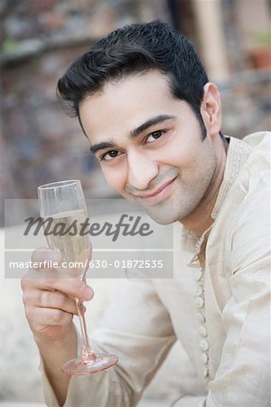 Porträt eines jungen Mannes holding ein Champagnerglas und Lächeln