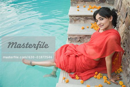 Portrait d'une jeune femme assise au bord de la piscine