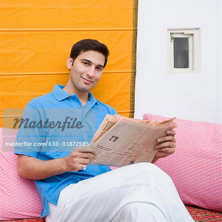 Portrait d'un jeune homme tenant un journal et ricaner