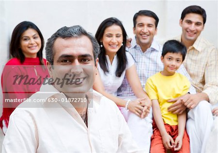 Portrait of a mid adult man smiling with his family smiling in the background