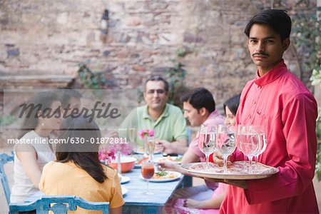 Portrait of a waiter serving water to guests