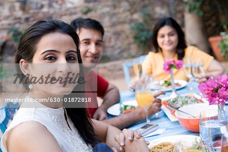 Portrait of a mid adult couple sitting with a mid adult woman at a dining table